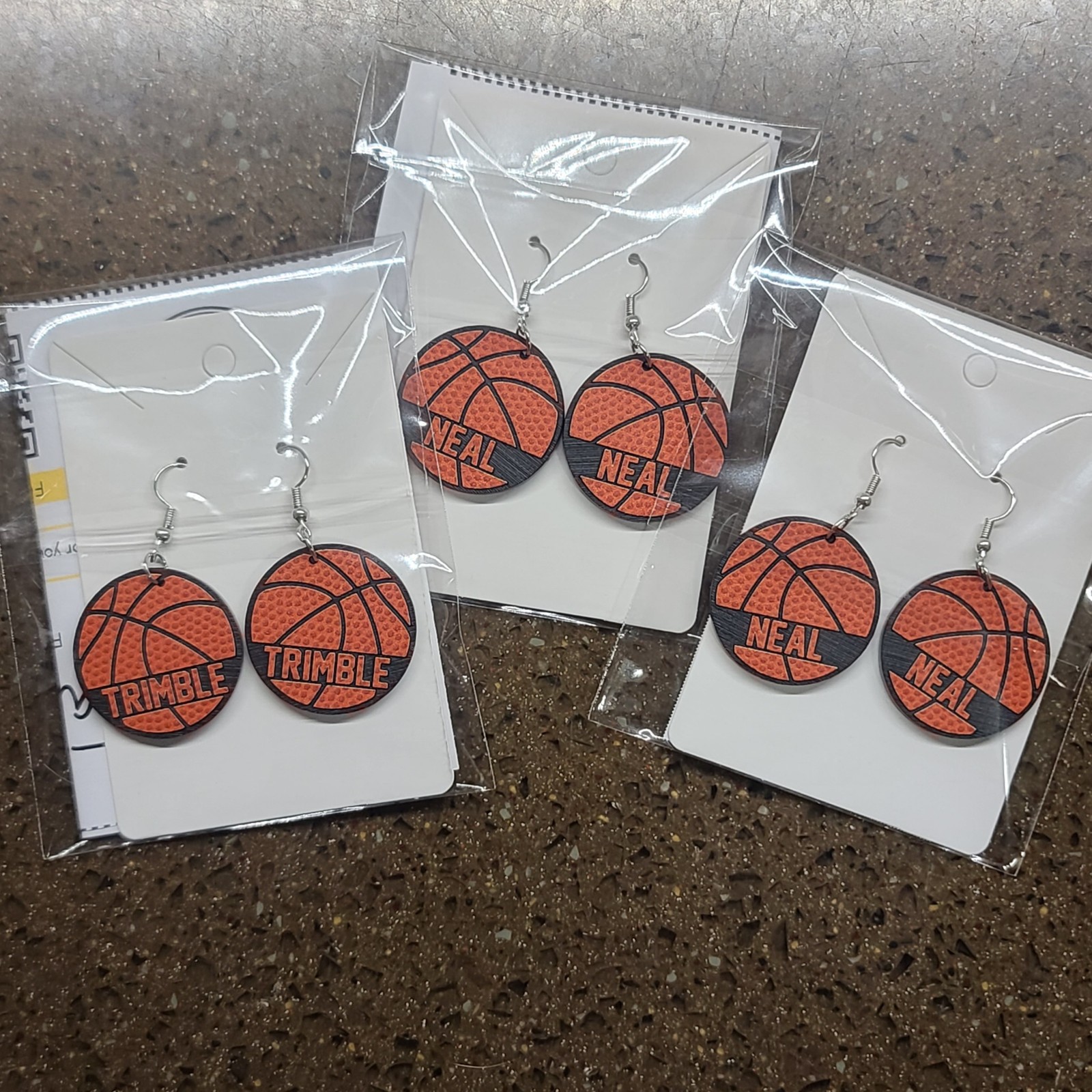 Three pairs of personalized basketball earrings in packaging